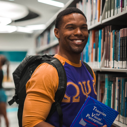 Male smiling holding book in the library.