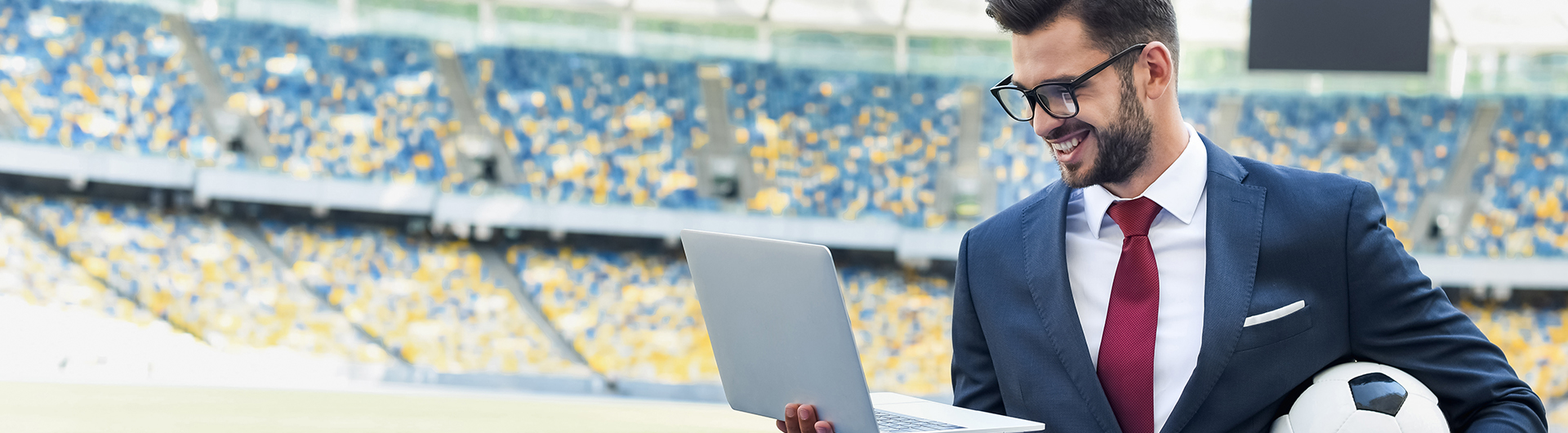 sports manager on field holding soccer ball and laptop
