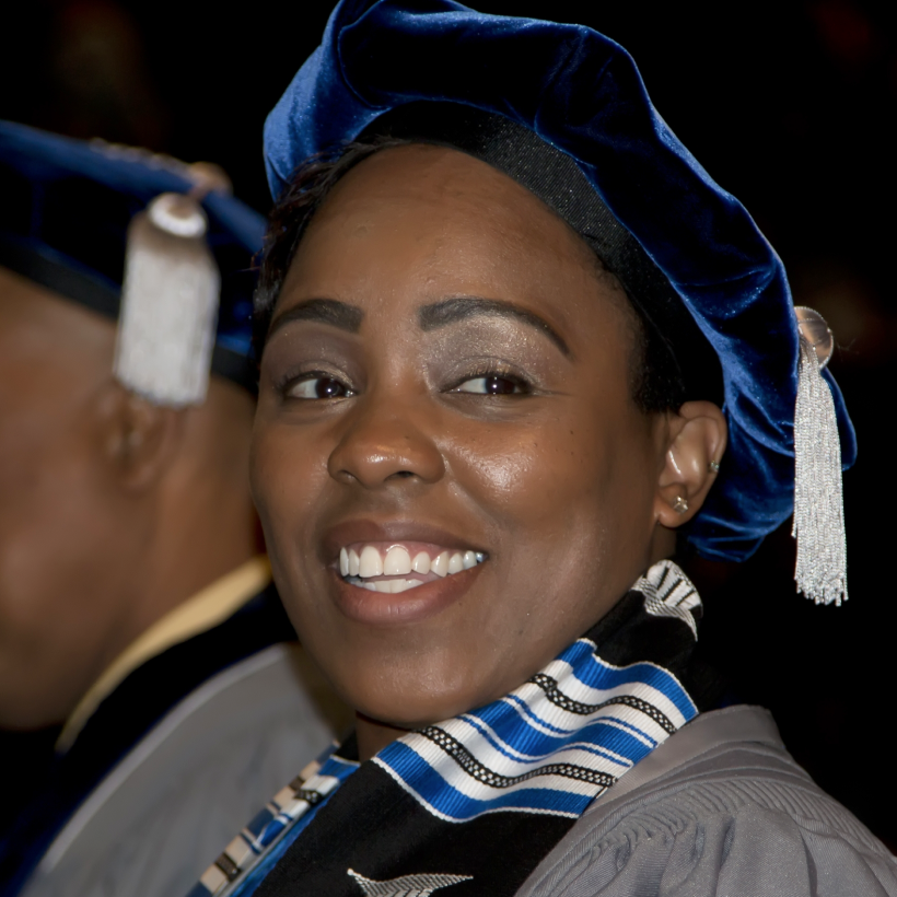 NSU Fischler College graduate in cap and gown smiling