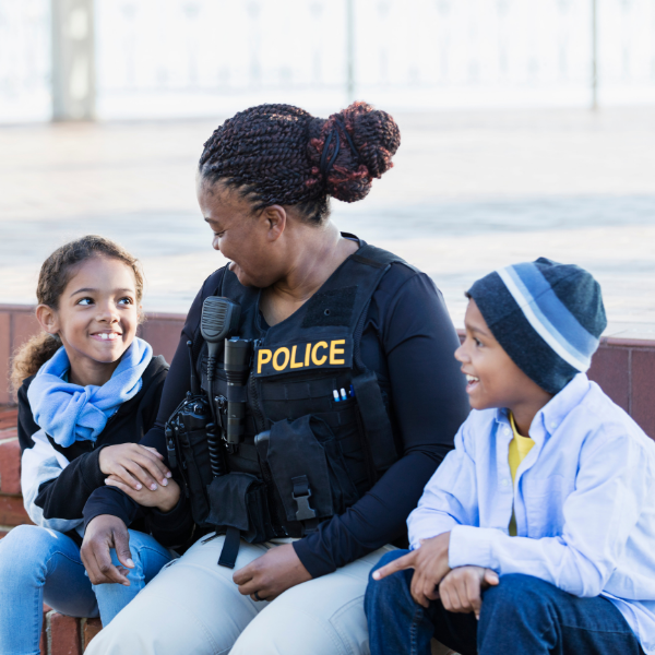 Criminal justice graduate in uniform seated with two children